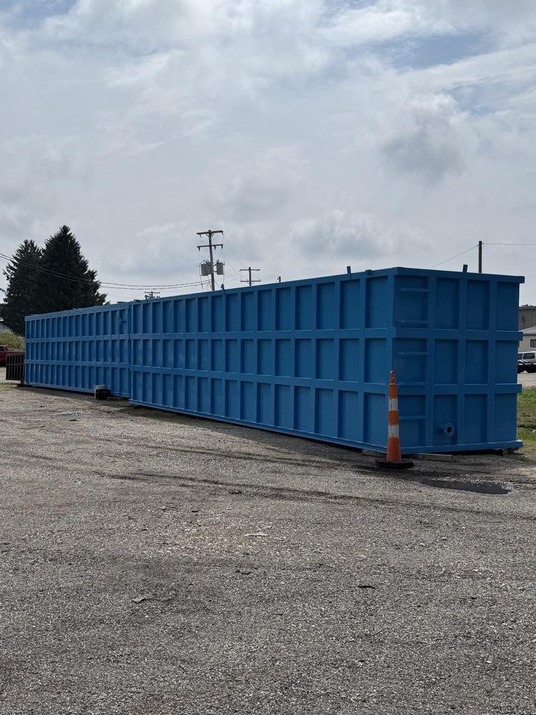 Full-length view of a 40 ft blue EnviroBox tank staged in the lot