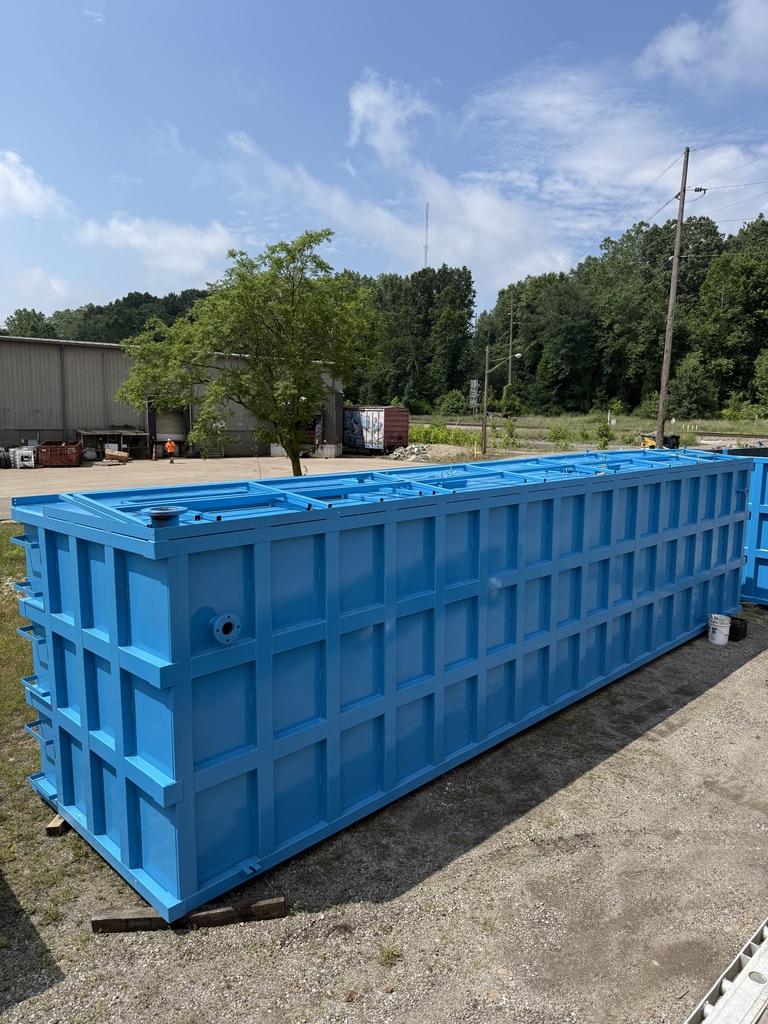 Open-top blue EnviroBox tank in the yard with flanged nozzle and full rib grid